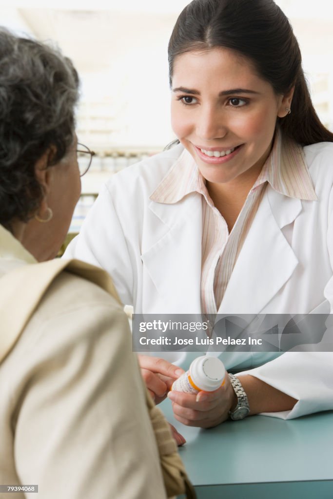 Hispanic female pharmacist discussing medication with customer