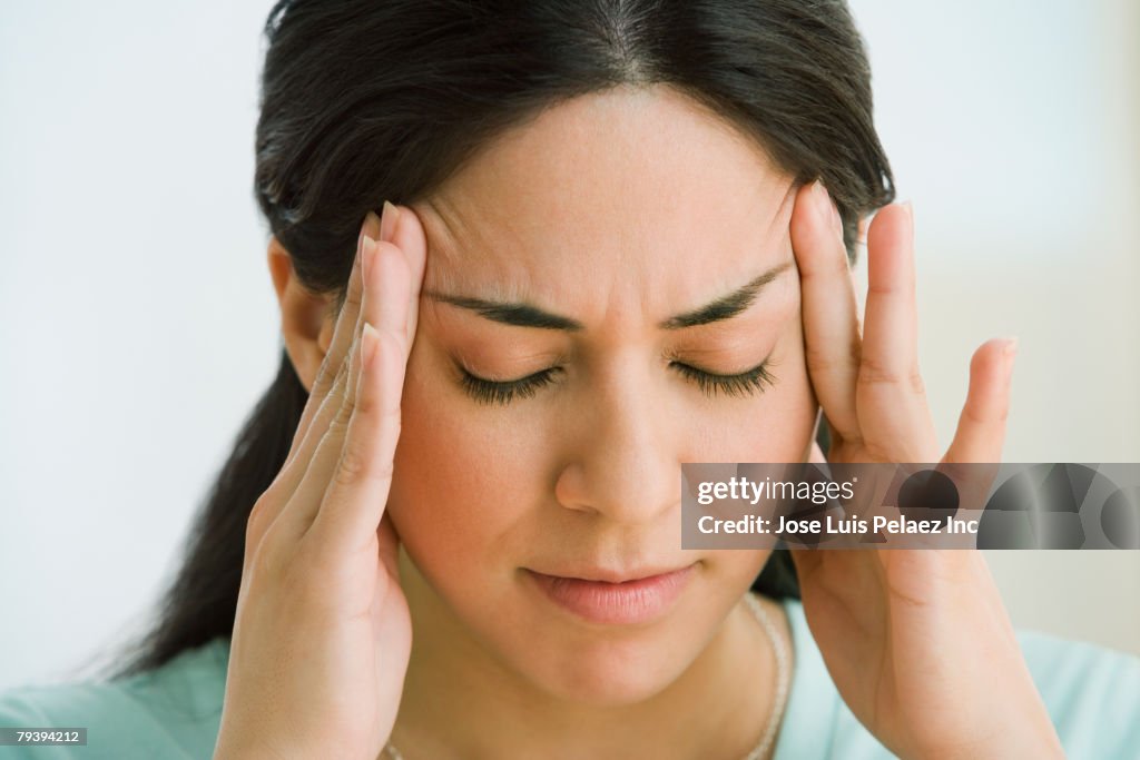 Hispanic woman rubbing forehead