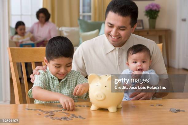 hispanic father and son with coins - couple saving piggy bank stock pictures, royalty-free photos & images