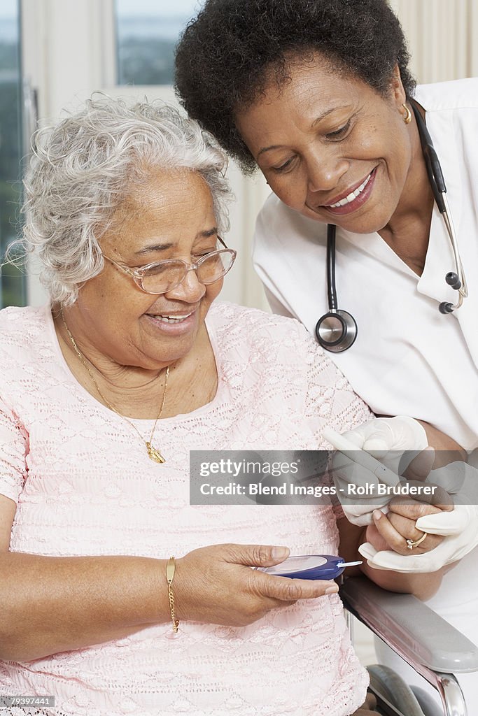 Doctor testing African American woman's blood sugar