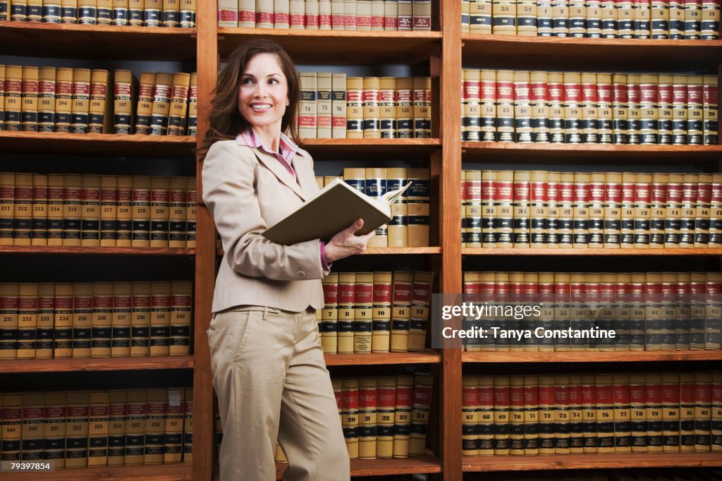 Hispanic woman reading library reference book