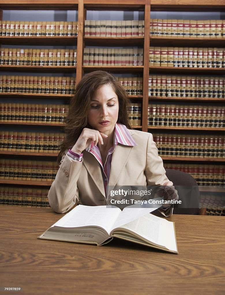Hispanic woman reading library reference book