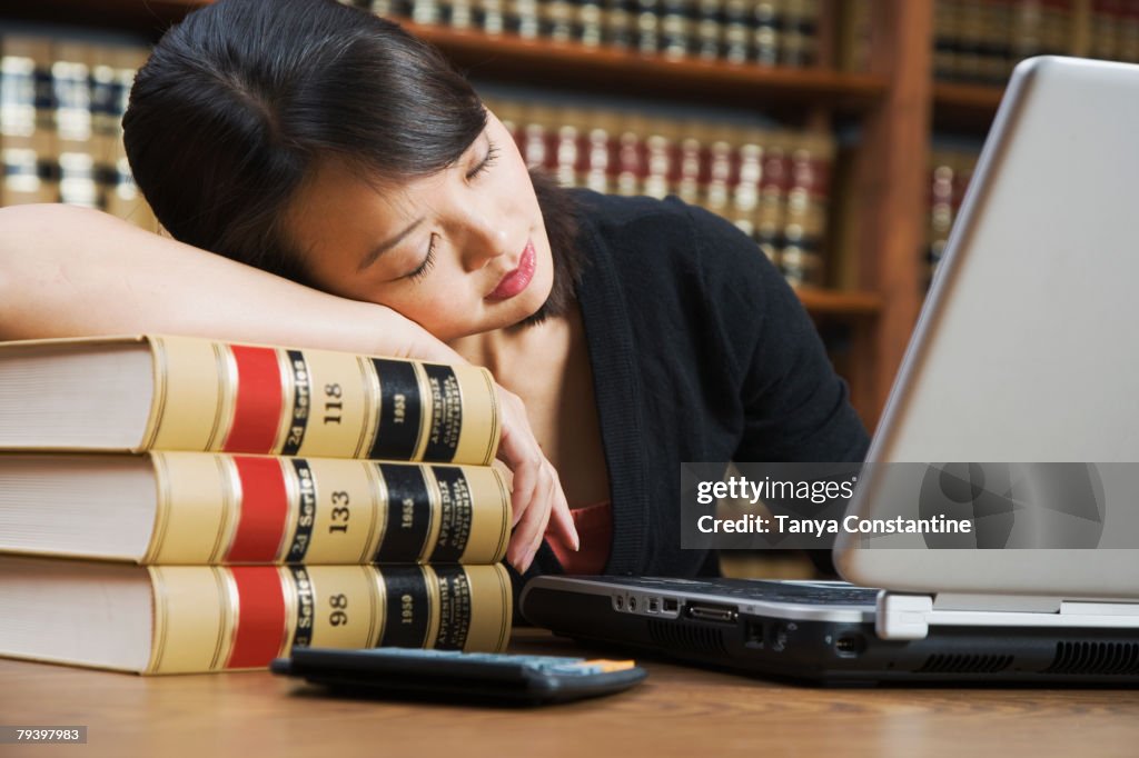 Asian woman sleeping on stack of library books