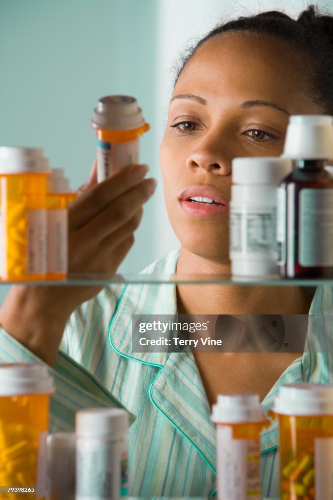 African American woman looking at medication bottle