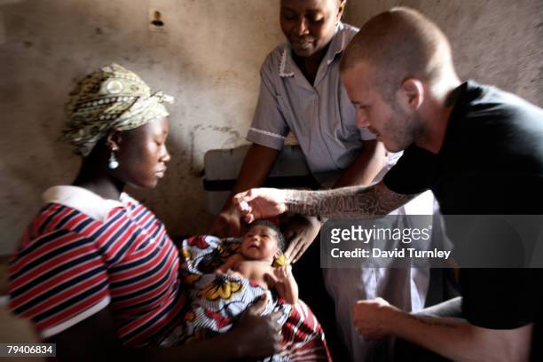 Goodwill Ambassador David Beckham administers a dose of oral polio vaccine to two-day-old Mariatsu as he joins nurse Angela on a visit to the...