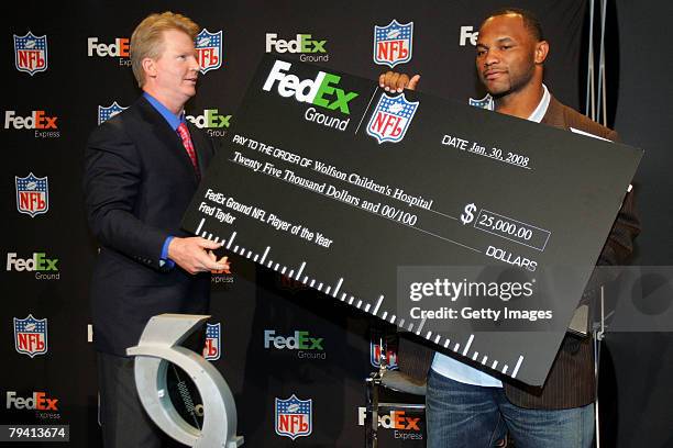 Former NFL quarterback Phil Simms and running back Fred Taylor of the Jacksonville Jaguars pose with the FedEx NFL Ground Award during the FedEx NFL...