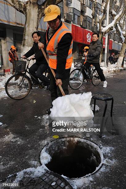 Chinese street sweeper shovels snow into a sewer outlet after heavy snowfalls hit the eastern Chinese city of Nanjing, 31 January 2008. China has...