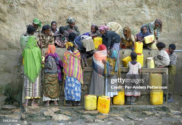 Women and children fetch water at a water tap in a rural village on February 7, 2001 outside Harar, Ethiopia. The area is supported by the aid...