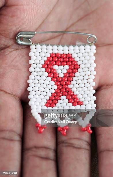 beaded aids ribbon badge on hand. grahamstown, eastern cape province, south africa - aids ribbon fotografías e imágenes de stock