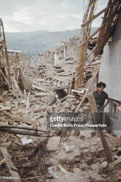 View of a man standing amid debris and destroyed houses in a town in Peru following the 1970 Ancash earthquake that hit the Ancash and La Libertad...