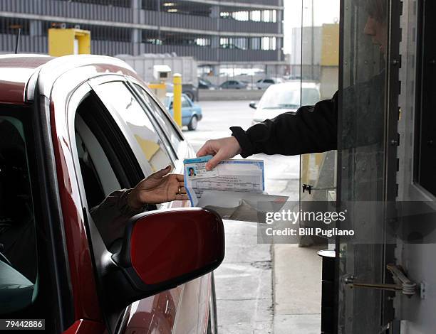 Driver hands her driver's license and birth certificate as proof of citizenship to a U.S. Customs & Border Protection agent at the Detroit/Windsor...