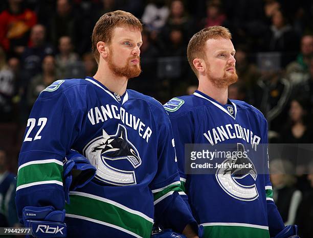 Henrik Sedin and Daniel Sedin of the Vancouver Canucks listen to the national anthems during their game against the Dallas Stars at General Motors...
