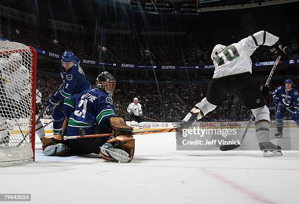 Drew MacIntyre of the Vancouver Canucks makes a save off the shot of Brenden Morrow of the Dallas Stars as Mattias Ohlund of the Canucks looks on...