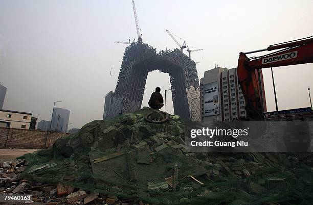 Worker looks at the China Central Television tower which is under construction at the Central Business District on January 14, 2008 in Beijing,...