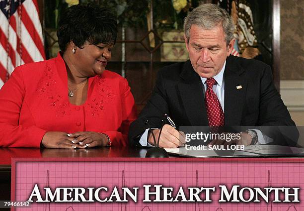 President George W. Bush signs a Presidential Proclamation in honor of American Heart Month as he sits next to heart disease survivor Joyce Cullen at...