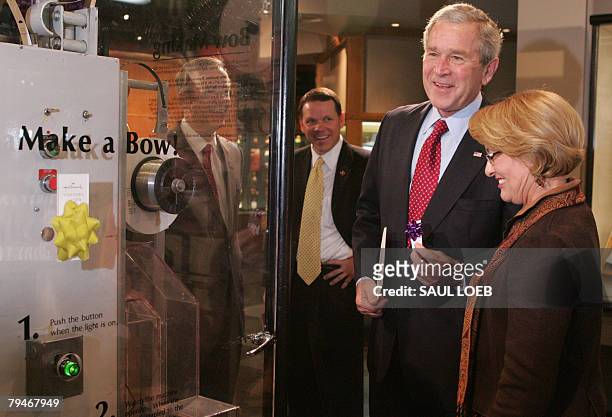 President George W. Bush holds a bow he made on a bow-making machine while touring Hallmark Cards with Rosemary Arroyo, director of the Hallmark...