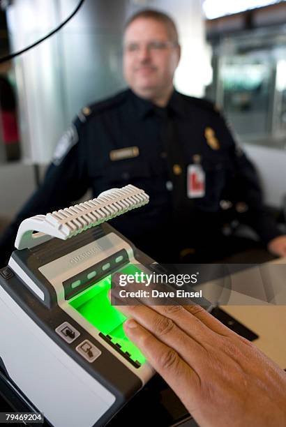 Customs and Border Protection officer Thomas Wuenschel looks on as an arriving passenger uses a new biometric scanner at George H. W. Bush...