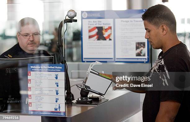 Customs and Border Protection officer Thomas Wuenschel monitors his screen as an arriving passenger uses a new biometric scanner at George H. W. Bush...