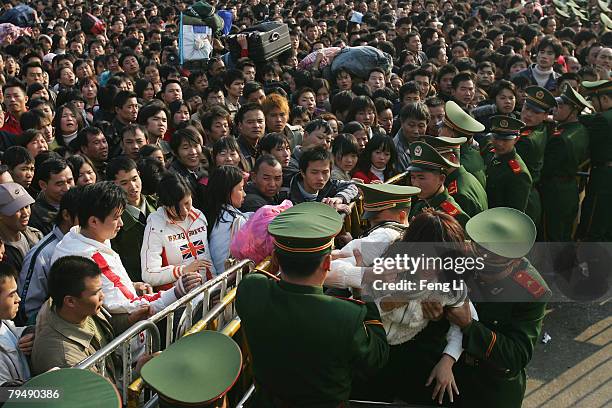 Armed police lift a woman that fainted as passengers wait stranded due to heavy snow at Guangzhou Railway Station on February 3, 2008 in Guangzhou of...