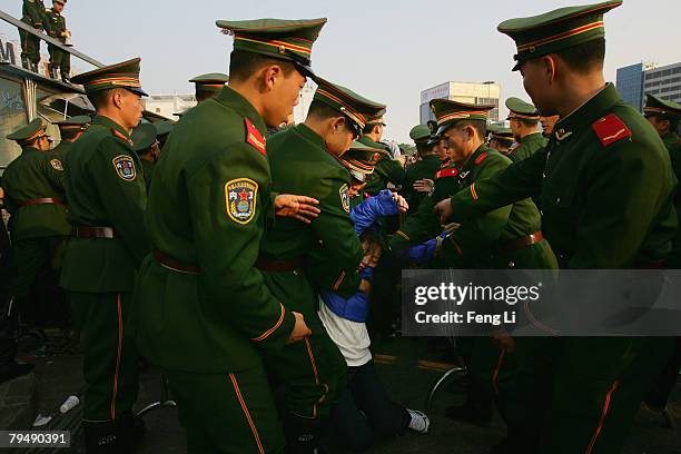 Armed police soldiers lift a woman that fainted as passengers wait stranded due to heavy snow at Guangzhou Railway Station on February 3, 2008 in...