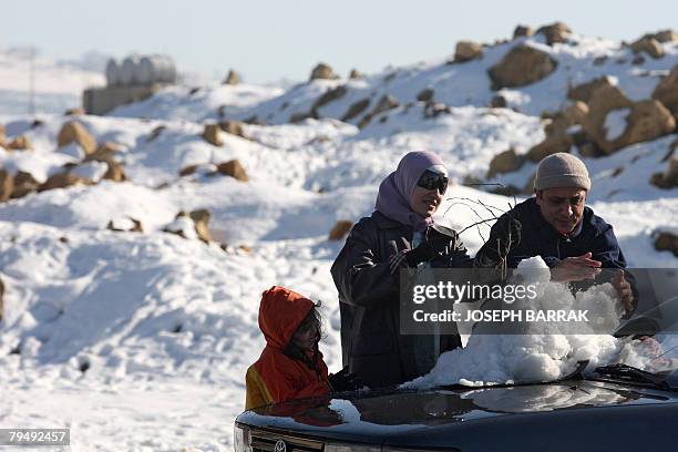 Lebanese family builds a snowman on a car in Aley, about 18 kms east of Beirut, 03 February 2008. Blankets of snow brought cities across the Middle...