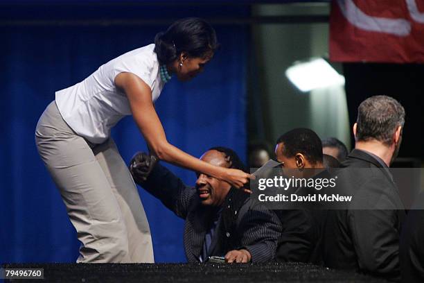 Musician Stevie Wonder is helped up after falling while ascending backstage stairs with Michelle Obama, wife of Democratic presidential hopeful U.S....