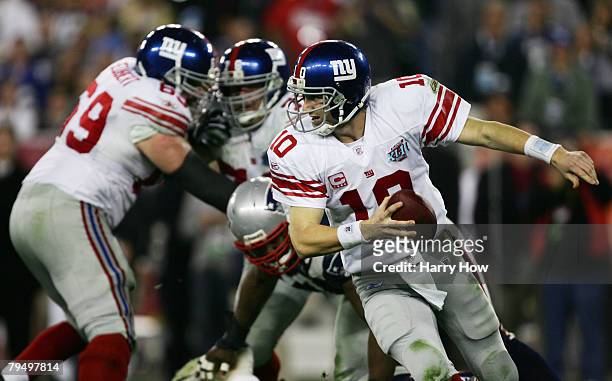Quarterback Eli Manning of the New York Giants scrambles away from the New England Patriots defense in the fourth quarter during Super Bowl XLII on...