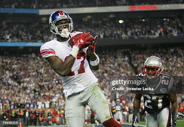 Wide receiver Plaxico Burress of the New York Giants catches a 13-yard touchdown pass in the fourth quarter over Ellis Hobbs of the New England...