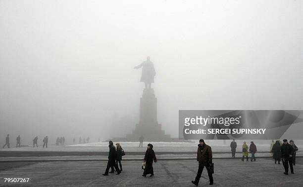 People pass Lenin's monument in the centre of the Ukrainian city of Kharkiv during a very foggy day on February 4, 2008. AFP PHOTO/ SERGEI SUPINSKY