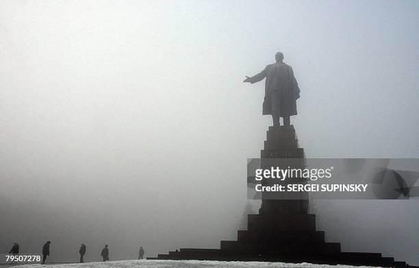 People pass Lenin's monument in the centre of the Ukrainian city of Kharkiv during a foggy day on February 4, 2008. AFP PHOTO/ SERGEI SUPINSKY