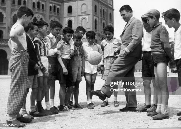 Hungarian-born Spanish footballer Ferenc Puskas shows a group of boys in Madrid his left-footed technique, 11th October 1961. He plays for Real...