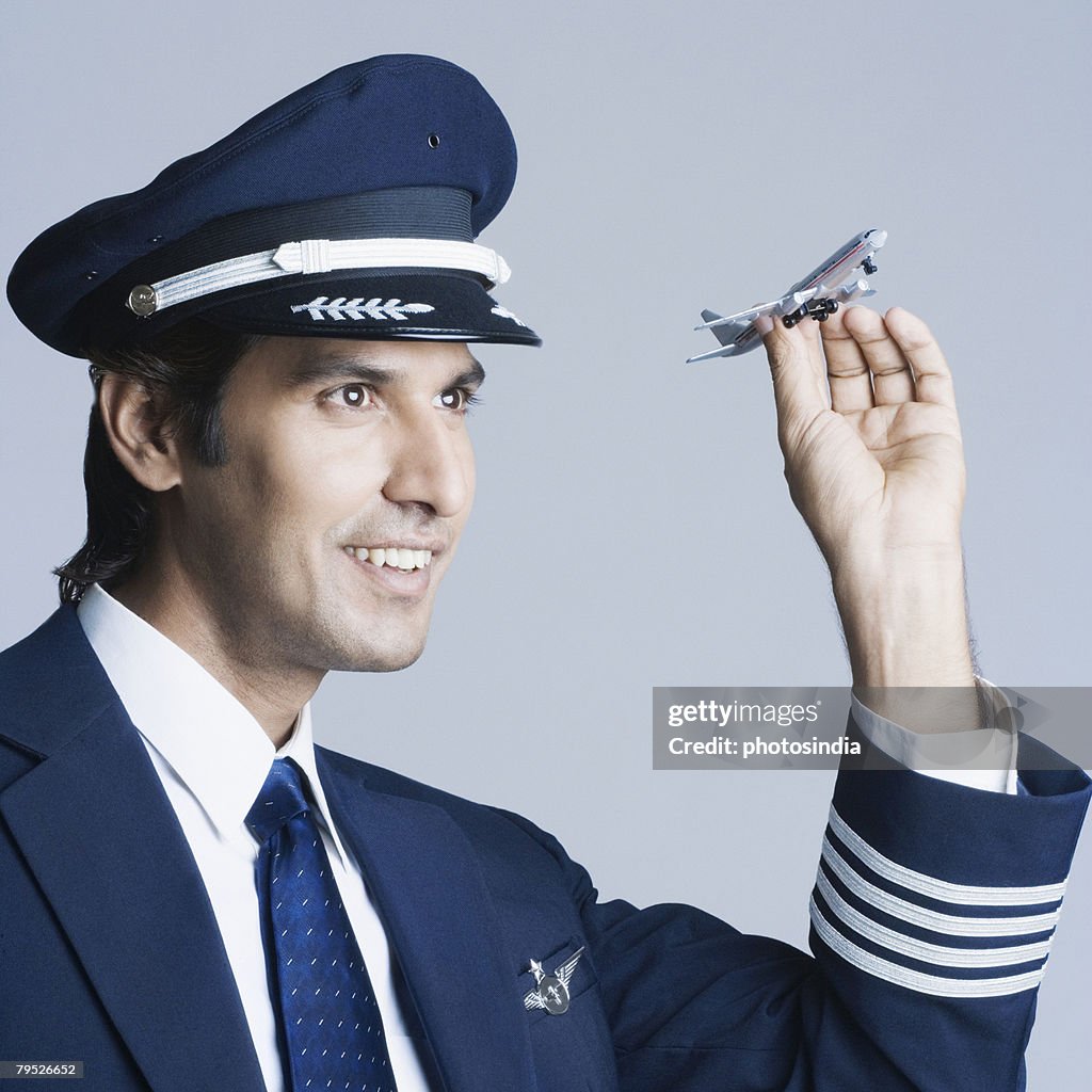 Close-up of a pilot holding a toy airplane and smiling