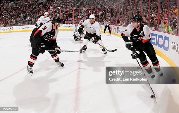 Simon Gagne and Scottie Upshall of the Philadelphia Flyers skates the puck along the boards against Todd Marchant of the Anaheim Ducks on February 2,...
