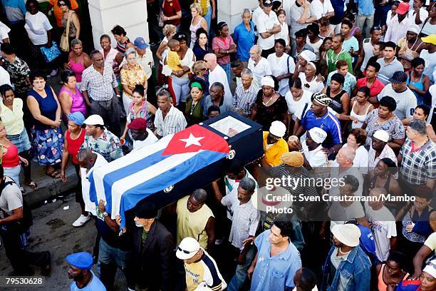 Cubans carry the coffin of Tata Guines, covered with a Cuban flag, through the streets of Guines on the way to the cementary, shortly before the...