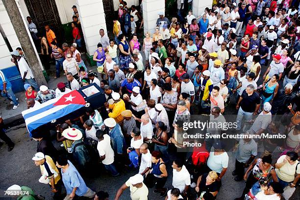 Cubans carry the coffin of Tata Guines, covered with a Cuban flag, through the streets of Guines on the way to the cementary, shortly before the...