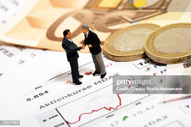 figurines shaking hands by euros - valuta stock pictures, royalty-free photos & images