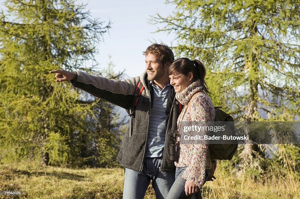 Young couple walking in meadow, man pointing