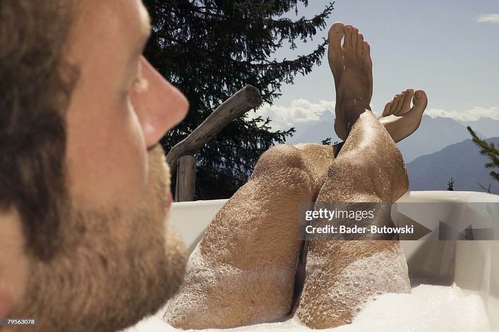 Young man lying in bathtub