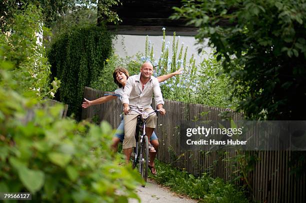 couple riding bicycle, smiling - arm span stockfoto's en -beelden