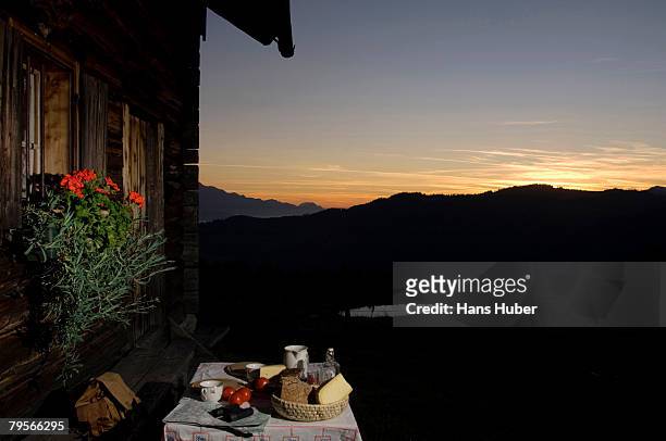 table with bread and cheese in front of alpine hut - alm hütte stock-fotos und bilder