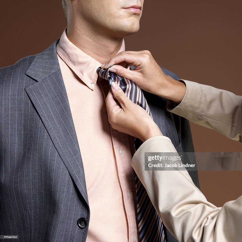 Woman binding businessman's tie