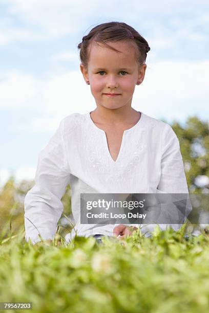 girl (7-9) sitting in meadow - plain background please stock-fotos und bilder