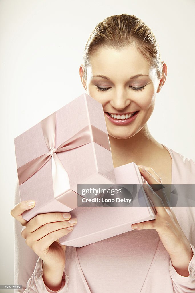 Young woman opening gift box, smiling, close-up