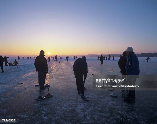 germany, bavaria, silhouette of people ice curling - curling sport stockfoto's en -beelden
