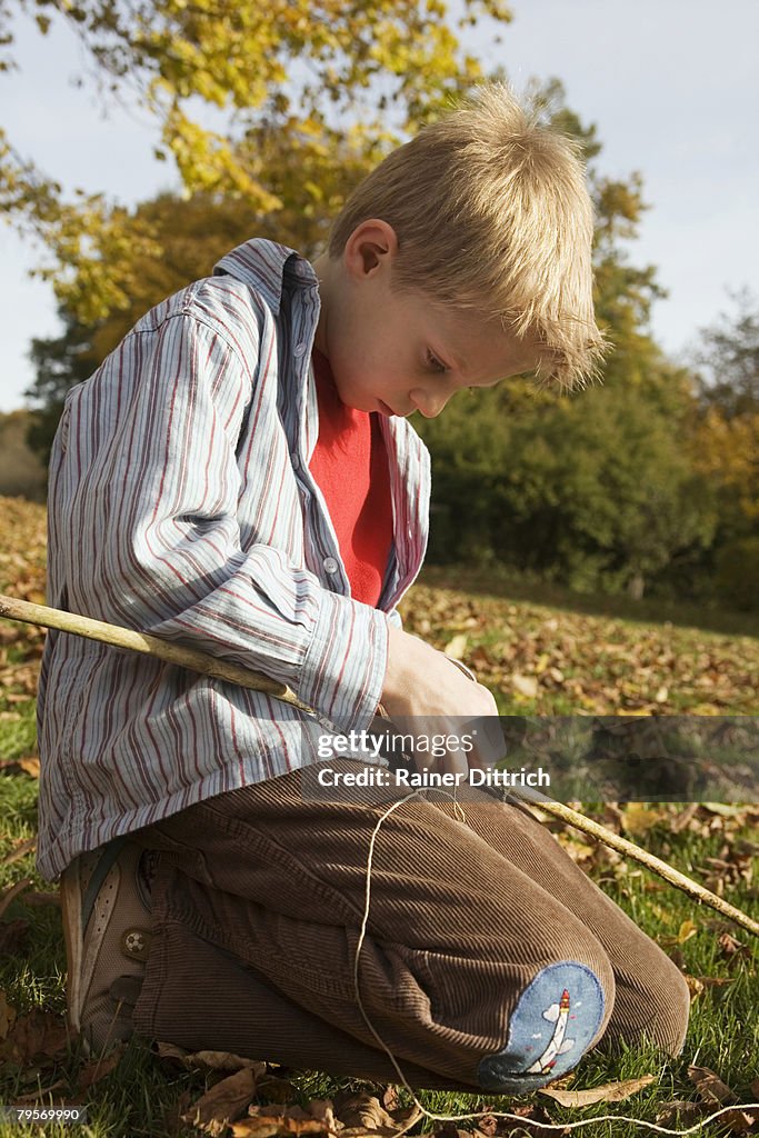 Boy (10-12) crafting fishing pole