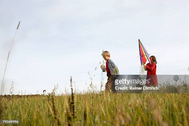 boy (10-12) and girl (7-9) flying kite - family time stock pictures, royalty-free photos & images