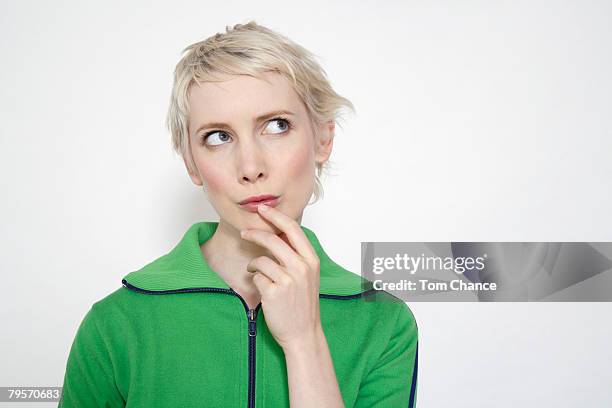 young woman with hand on her chin, portrait - indécision photos et images de collection