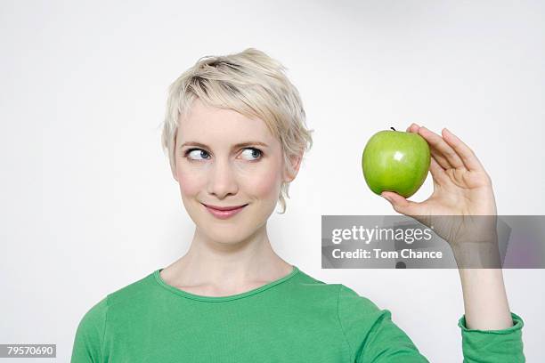 young woman holding a green apple, portrait - woman short blonde hair stock pictures, royalty-free photos & images