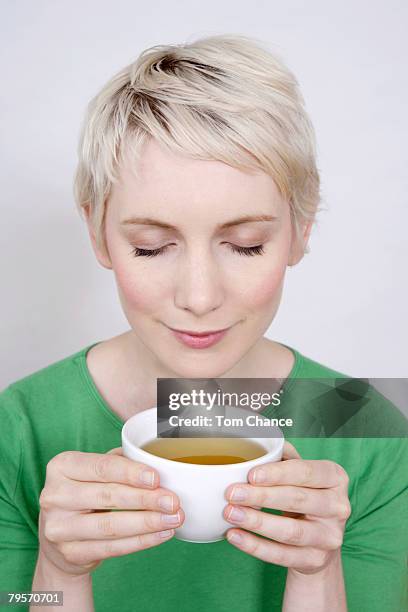 young woman holding tea bowl, portrait - indulgence white background stockfoto's en -beelden