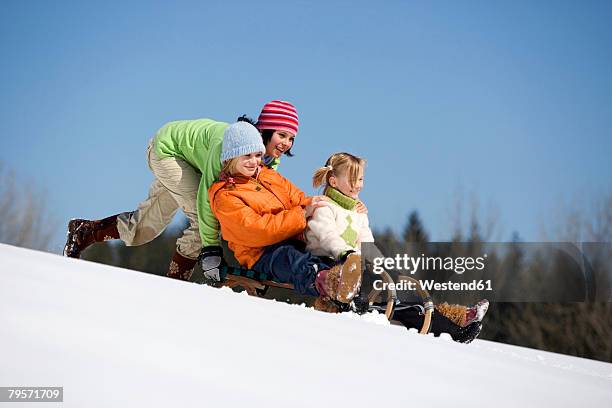 three children on sledge - girl 11 12 laughing close up foto e immagini stock